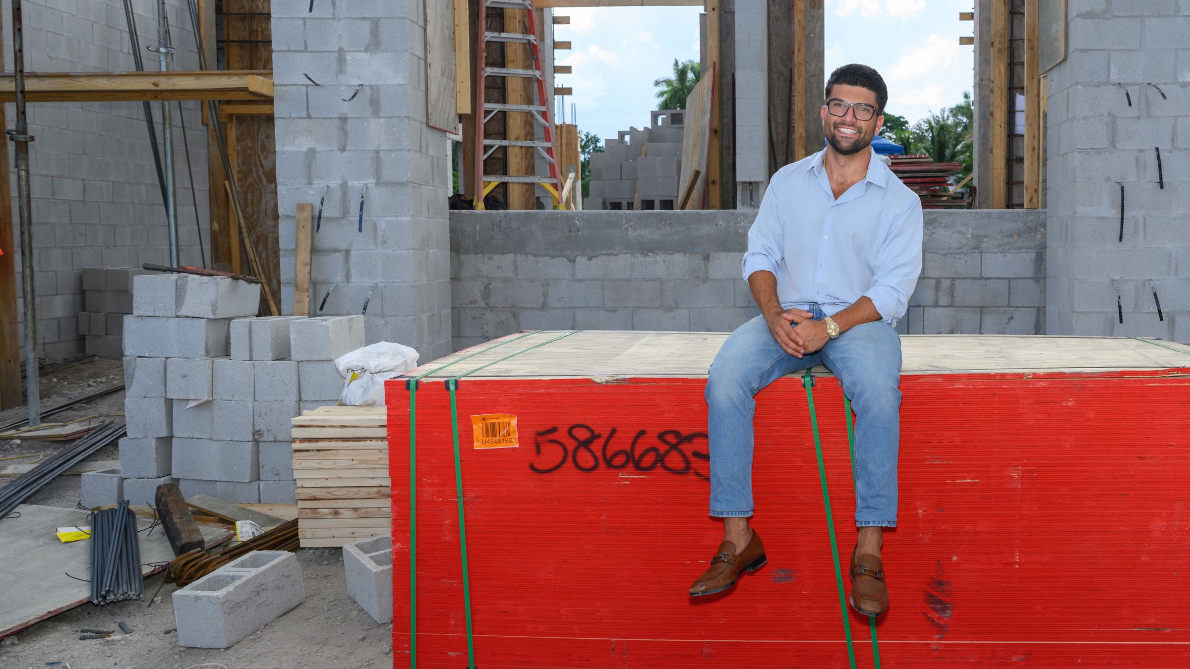 Nicholas Napoli seated on a wrapped bundle of building materials at one of his residential construction sites